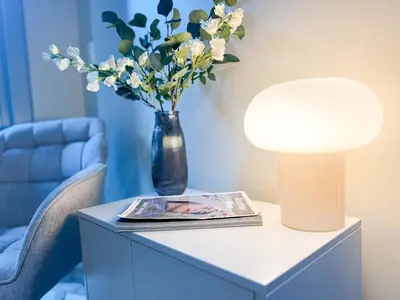 a table with a lamp and a vase with flowers on it at Prime 1BR Condo in the Heart of BGC #upt12j in Manila