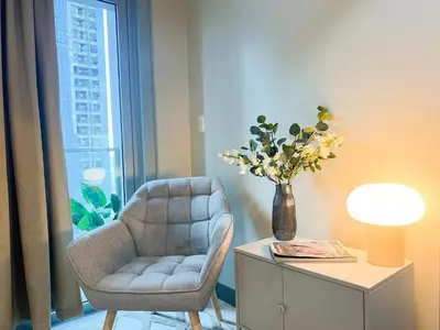 a living room with a chair and a vase of flowers at Prime 1BR Condo in the Heart of BGC #upt12j in Manila