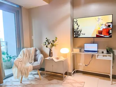 a living room with a chair and a tv on the wall at Prime 1BR Condo in the Heart of BGC #upt12j in Manila