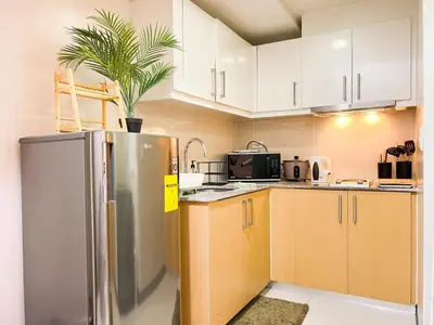 a kitchen with a stainless steel refrigerator and white cabinets at Prime Uptown BGC | Stylish 1BR Getaway #upt1 35j in Manila