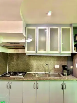 a kitchen with white cabinets and a sink at Entire Condo loft in Mandaluyong in Manila
