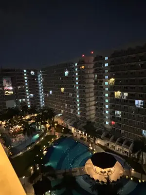 a view of a large building with a pool at night at Shell Residences Near Moa and Naia Airport- Rhoi in Manila