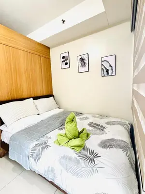 a bedroom with a bed with a green towel on it at Shell Residences Near Moa and Naia Airport- Rhoi in Manila