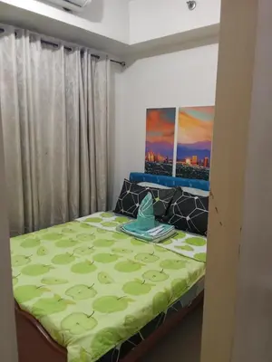 a bedroom with a bed with a green comforter at Sea Residences david in Manila
