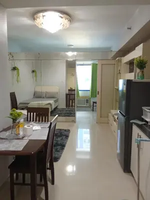 a kitchen and a living room with a table and a refrigerator at Sea Residences david in Manila