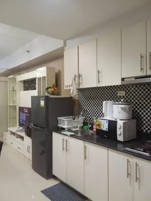 a kitchen with white cabinets and a black refrigerator at Sea Residences david in Manila