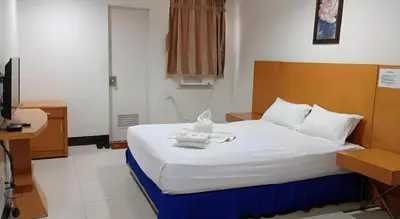 a bedroom with a bed with white sheets and a desk at Jeamco Royal Hotel - Pasig in Manila