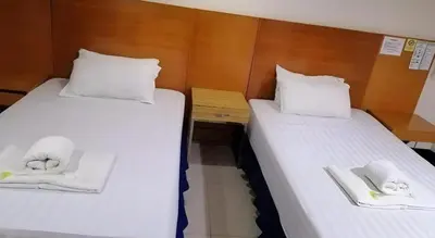 two beds in a room with white towels on them at Jeamco Royal Hotel - Pasig in Manila