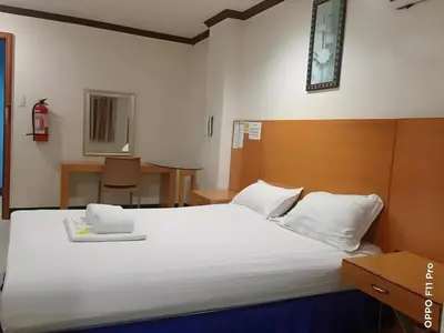 a bedroom with a large white bed with a wooden headboard at Jeamco Royal Hotel - Pasig in Manila