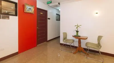 a hallway with a table and chairs and a red door at RedDoorz @ Gerlins Lodge Two in Manila