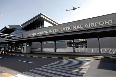 an airport terminal with an airplane flying over it at Sybaysuites staycation near Okada COD MOA NAIA in Manila