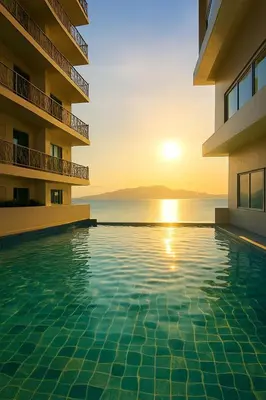 a swimming pool in front of a building with the sunset at Modern & Cozy 2BR near Okada, Solaire, Airport in Manila