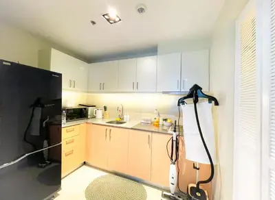 a kitchen with white cabinets and a black refrigerator at Modern & Cozy 6BR near Okada, Solaire, Airport in Manila