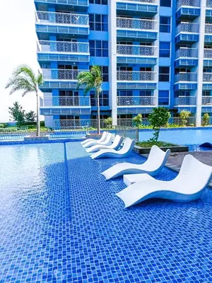 a swimming pool with white chairs in front of a tall building at Modern & Cozy 6BR near Okada, Solaire, Airport in Manila