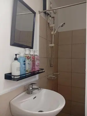 a bathroom sink with a mirror and a shower at Nikki's cozy home makati in Manila