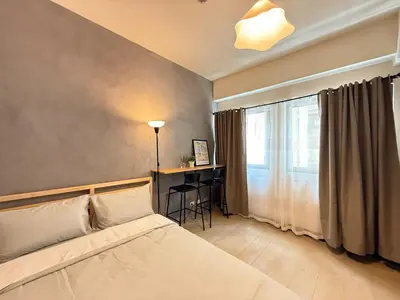 a bedroom with a bed and a desk and a window at Cozy Studio in Salcedo Village Makati in Manila