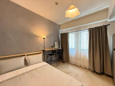 a bedroom with a bed and a desk and a window at Cozy Studio in Salcedo Village Makati in Manila