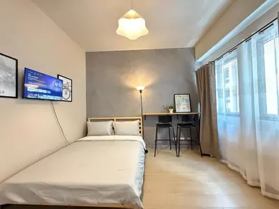 a bedroom with a bed and a table and a window at Cozy Studio in Salcedo Village Makati in Manila