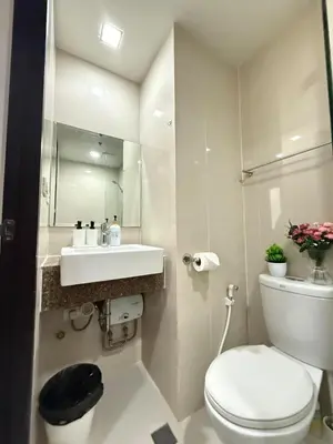 a bathroom with a toilet and a sink and a mirror at Cozy Studio in Salcedo Village Makati in Manila