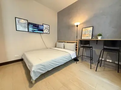 a bedroom with a bed and a desk and a tv at Cozy Studio in Salcedo Village Makati in Manila