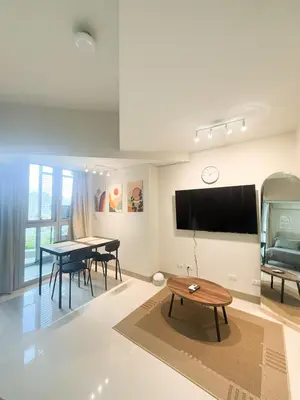 a living room with a table and a flat screen tv at City View Stay in Uptown BGC in Manila