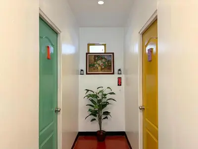 a hallway with two doors and a potted plant at Dormitelsph BGC in Manila