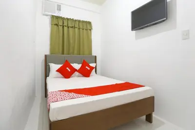 a bedroom with a bed with red pillows and a tv at OYO 736 Jade Apartelle in Cabuyao