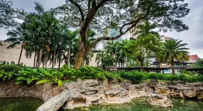 a park with a rock wall and trees and water at City Stay Inns Slex Makati in Manila