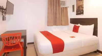 a bedroom with a bed and a red chair at City Stay Inns Slex Makati in Manila