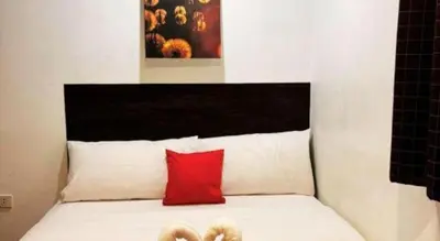 a bed with a red pillow and a black headboard at City Stay Inns Slex Makati in Manila