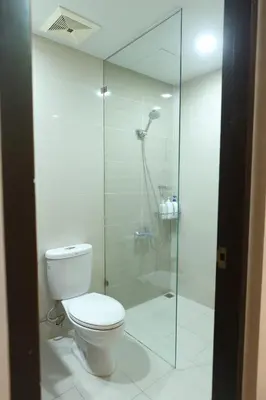 a bathroom with a toilet and a glass shower at 1BR condo at One Uptown Residence in BGC in Manila