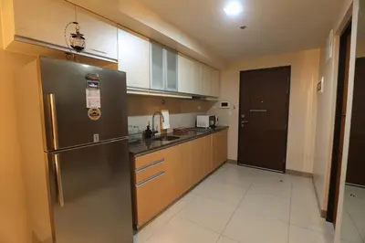a kitchen with a stainless steel refrigerator and wooden cabinets at 1BR condo at One Uptown Residence in BGC in Manila