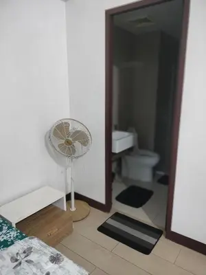 a bedroom with a fan and a bathroom at Pasay Condotel Near Airports in Manila