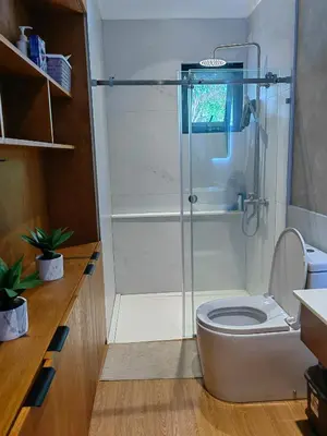 a bathroom with a toilet with a glass shower at The LakeFront Villa in Binangonan