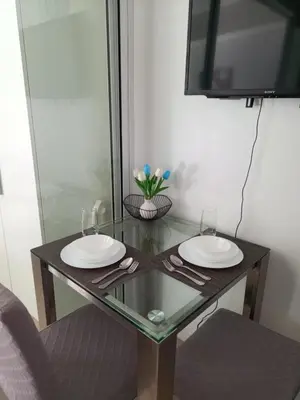 a glass table with two white plates and a tv at Azure Urban Resort Residences in Manila