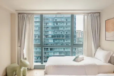 a bedroom with a large window with a view of a building at Family 2 Bedroom and 1 living Room Suite with Balcony - One Uptown, BGC in Manila