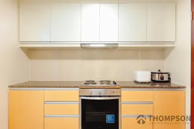 a kitchen with white cabinets and a stove top oven at Family 2 Bedroom and 1 living Room Suite with Balcony - One Uptown, BGC in Manila