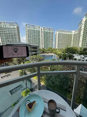 a table with a plate of food on a balcony with buildings at AZURE BICUTAN BORACAY 4FL BEACH POOL View in Manila