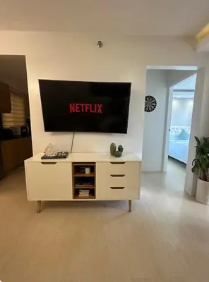 a white entertainment center with a television on a wall at Modern Minimalist Luxe Retreat 2 Bedroom with parking in Manila