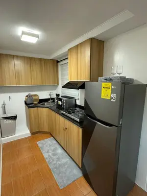 a kitchen with a black refrigerator and wooden cabinets at Modern Minimalist Luxe Retreat 2 Bedroom with parking in Manila