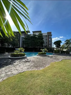 a building with a swimming pool and a palm tree at Modern Minimalist Luxe Retreat 2 Bedroom with parking in Manila
