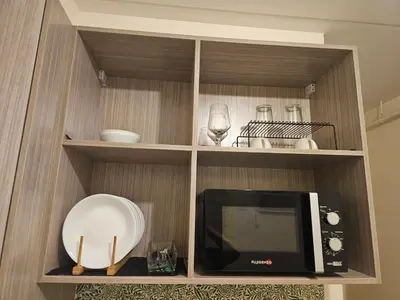 a kitchen with a microwave and a plate on a shelf at Entire Studio Unit Classio De Condotel at Urban Deca Cubao in Manila