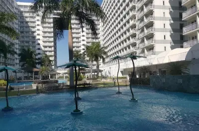 a swimming pool with umbrellas in the water with buildings at Sebby's staycation at Shell MOA in Manila