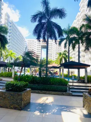 a park with palm trees and a large building at Sebby's staycation at Shell MOA in Manila