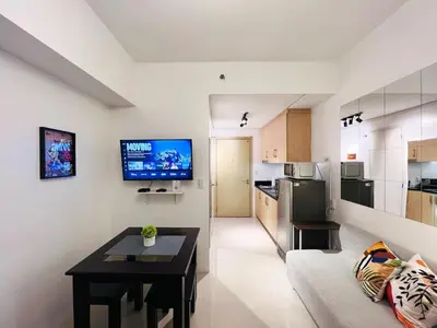 a living room with a couch and a tv on a wall at 1BR Condotel with Balcony at SM Light Residences #LT01-1 in Manila