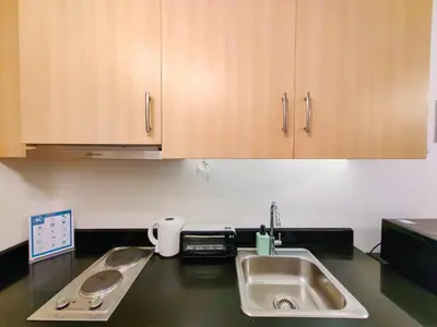 a kitchen counter with a sink and wooden cabinets at 1BR Condotel with Balcony at SM Light Residences #LT02-1 in Manila