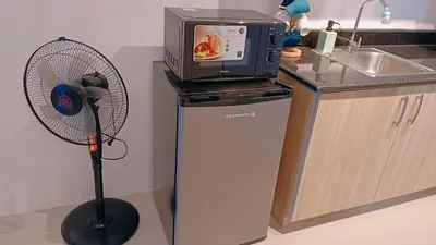 a kitchen with a microwave and a fan next to a refrigerator at 1BR Condotel with Balcony at SM Light Residences #LT04-1 in Manila