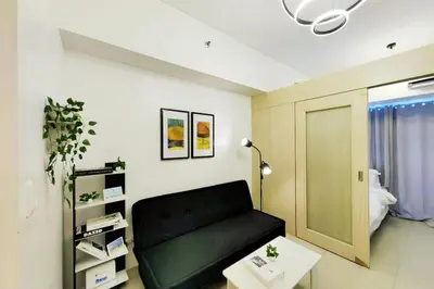 a living room with a black couch and a table at 1BR Condotel with Balcony at SM Light Residences #LT05-1 in Manila