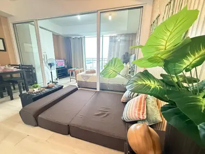 a living room with a large bed and some plants at AZURE BICUTAN-MAUI 1631 City View in Manila