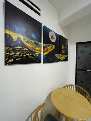 a room with four paintings on a wall with a table at D and A Transient Inn Taguig in Taguig